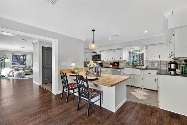 a kitchen with a dining table chairs wooden floor appliances and cabinets