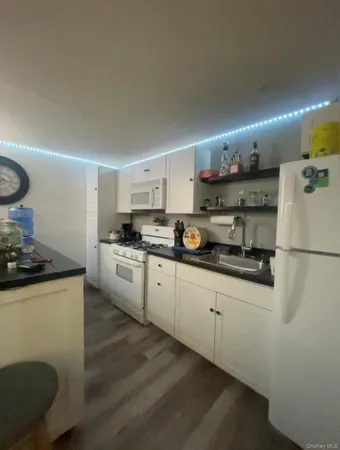 a kitchen with granite countertop a sink a stove a refrigerator and cabinets