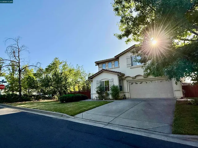 a view of a white house next to a yard with big trees