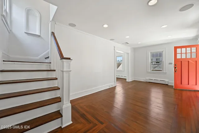 a view of an empty room with wooden floor and stairs