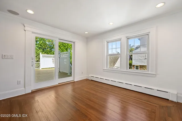 an empty room with wooden floor and windows