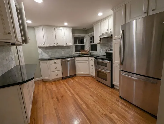 a kitchen with granite countertop stainless steel appliances a refrigerator a stove top oven and sink