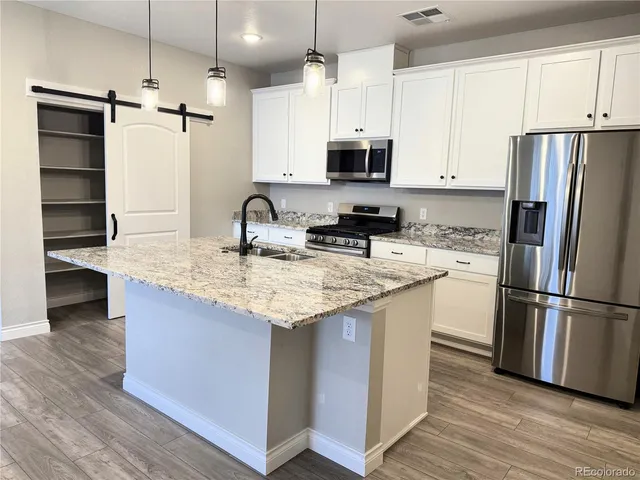 a kitchen with stainless steel appliances granite countertop a refrigerator a stove a sink and a microwave