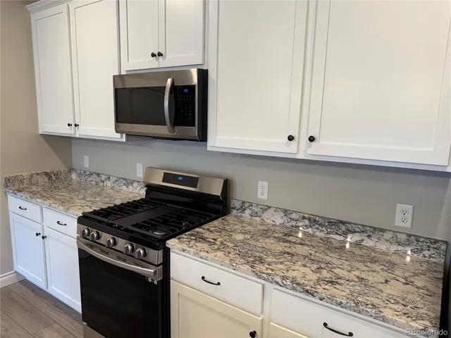 a kitchen with granite countertop white cabinets and stainless steel appliances