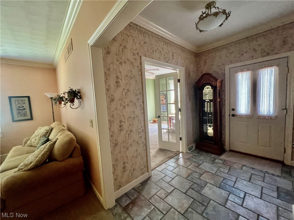 Tiled entryway featuring crown molding