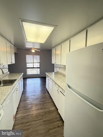 a kitchen with stainless steel appliances a sink and wooden floors
