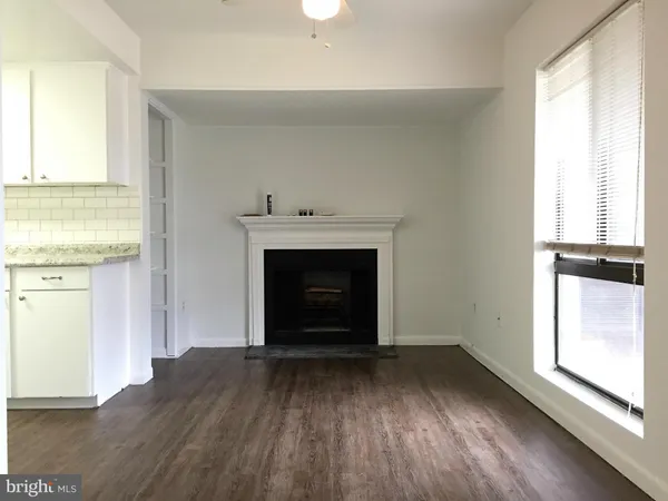 an empty room with wooden floor a fireplace and windows