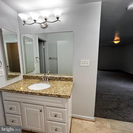 a bathroom with a granite countertop sink a mirror and a shower