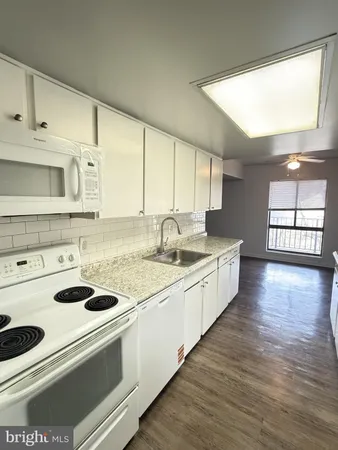 a kitchen with granite countertop a sink and cabinets with wooden floors