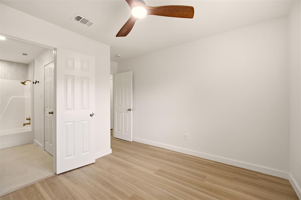 908 Isbell Road, Unit A Fort Worth, TX 76114 - Photo 20 of 28 Room featuring wood-finish flooring, a ceiling fan with wooden blades, white trim, and a white six-panel door