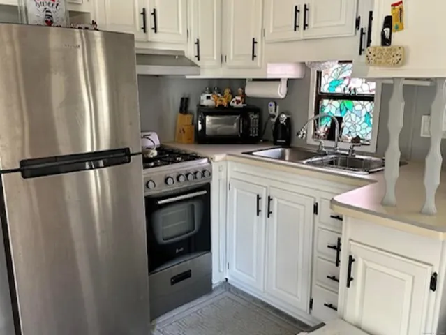 a kitchen with stainless steel appliances a refrigerator a stove and white cabinets