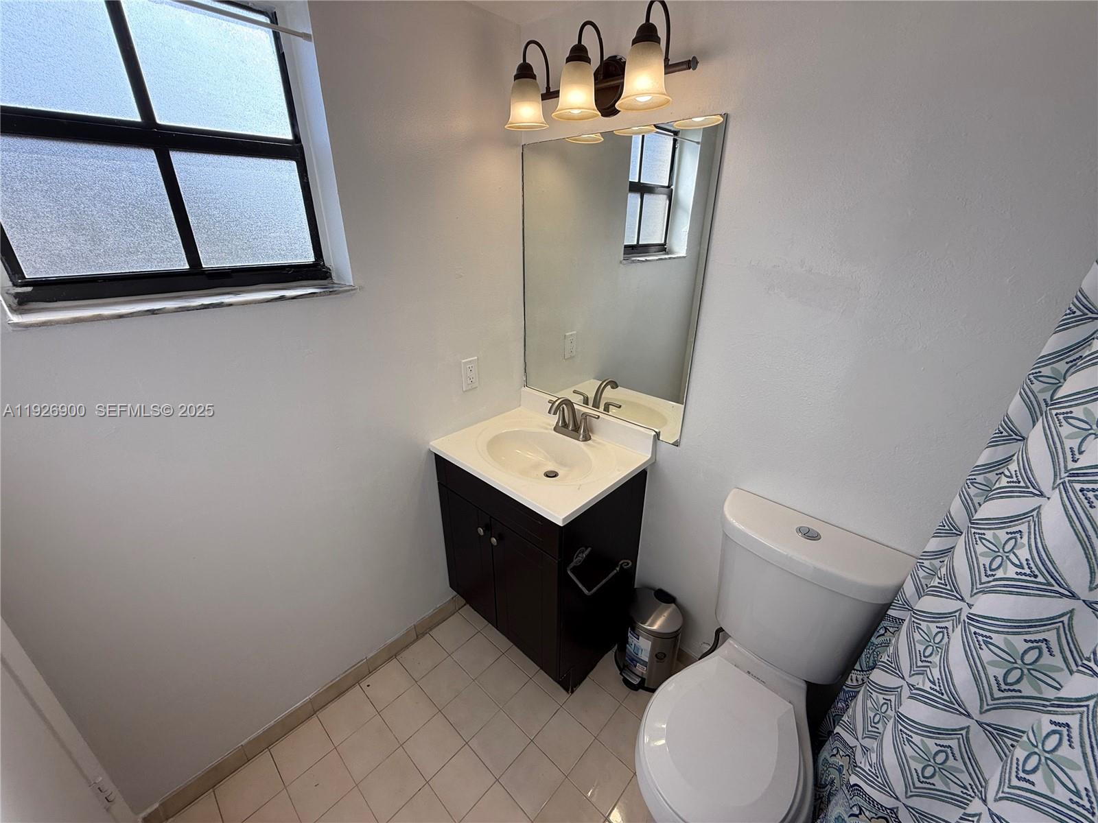 15969 Northwest 64th Avenue, Unit 504 Miami Lakes, FL 33014 - Photo 12 of 21 a bathroom with a toilet sink and mirror