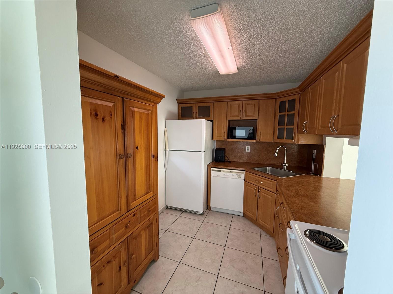 15969 Northwest 64th Avenue, Unit 504 Miami Lakes, FL 33014 - Photo 8 of 21 a kitchen with a refrigerator a stove top oven and cabinets