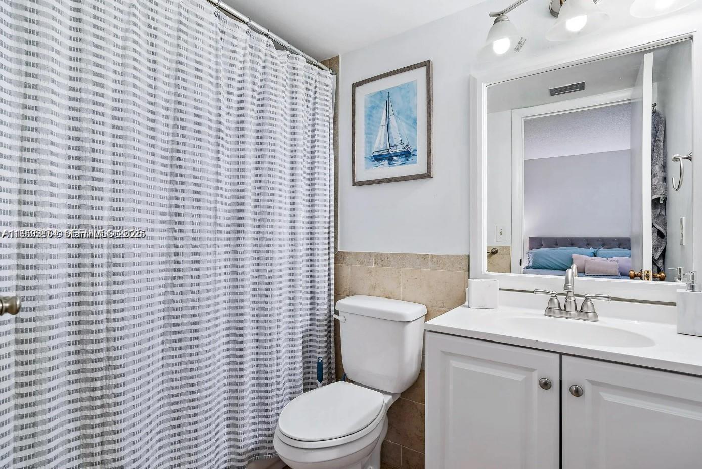 1605 Highway 1, Unit D104 Jupiter, FL 33477 - Photo 18 of 22 a bathroom with a toilet a sink a mirror and shower curtain