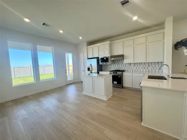 a large kitchen with stainless steel appliances granite countertop a stove a sink and a microwave
