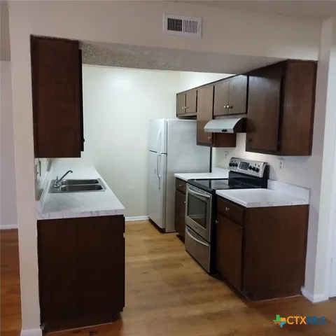 a kitchen with granite countertop a sink and a stove top oven