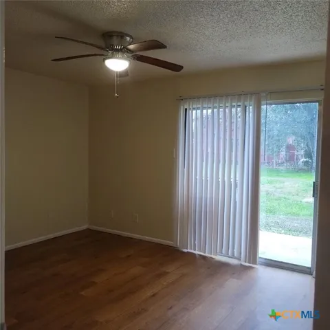 a view of an empty room with a window and hardwood floor