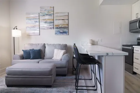 a living room with furniture a flat screen tv and a table