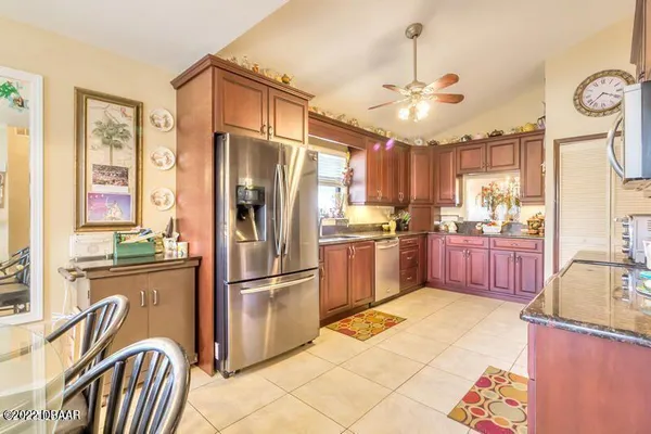 a kitchen with granite countertop stainless steel appliances a refrigerator oven a sink a dining table and chairs with wooden floor