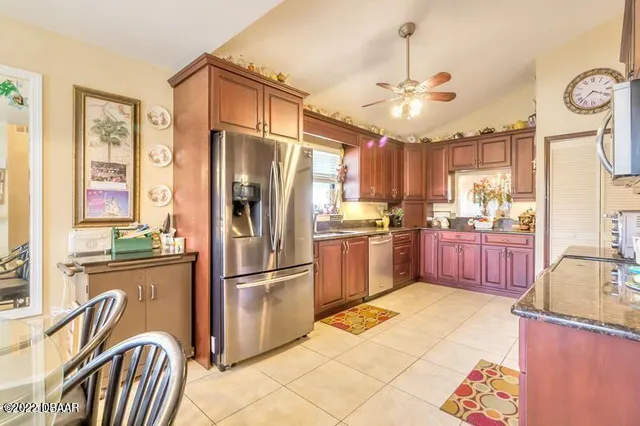 a kitchen with granite countertop stainless steel appliances a refrigerator oven a sink a dining table and chairs with wooden floor