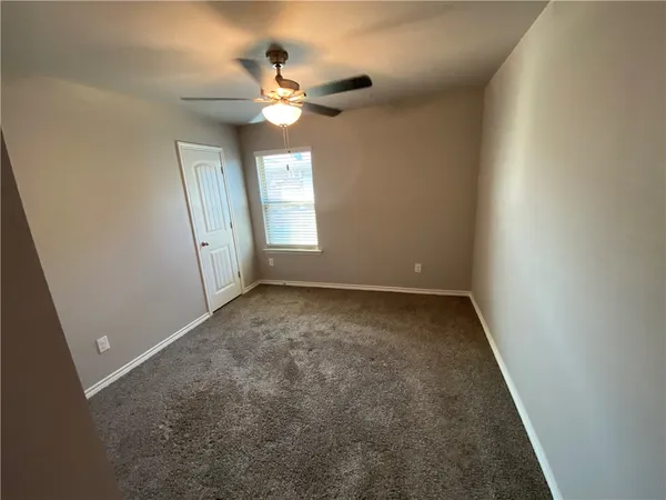 an empty room with a chandelier fan and windows