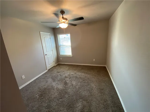 an empty room with a chandelier fan and windows