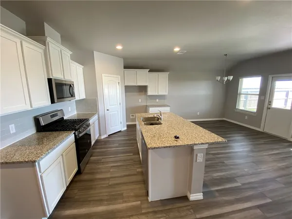 a kitchen with a stove and a wooden floor