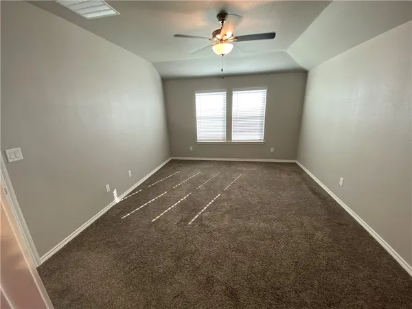 an empty room with a chandelier fan and windows