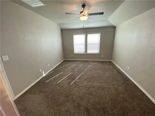 an empty room with a chandelier fan and windows