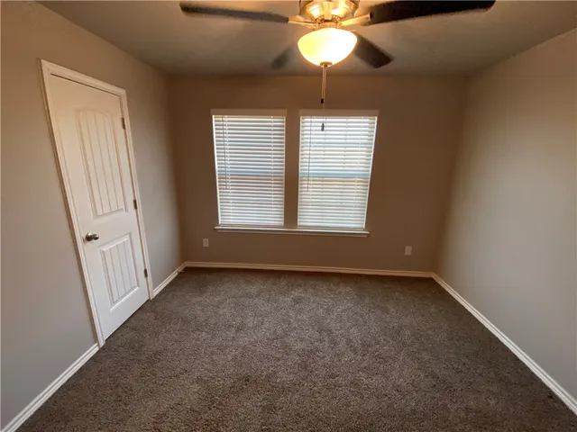 an empty room with a chandelier fan and windows