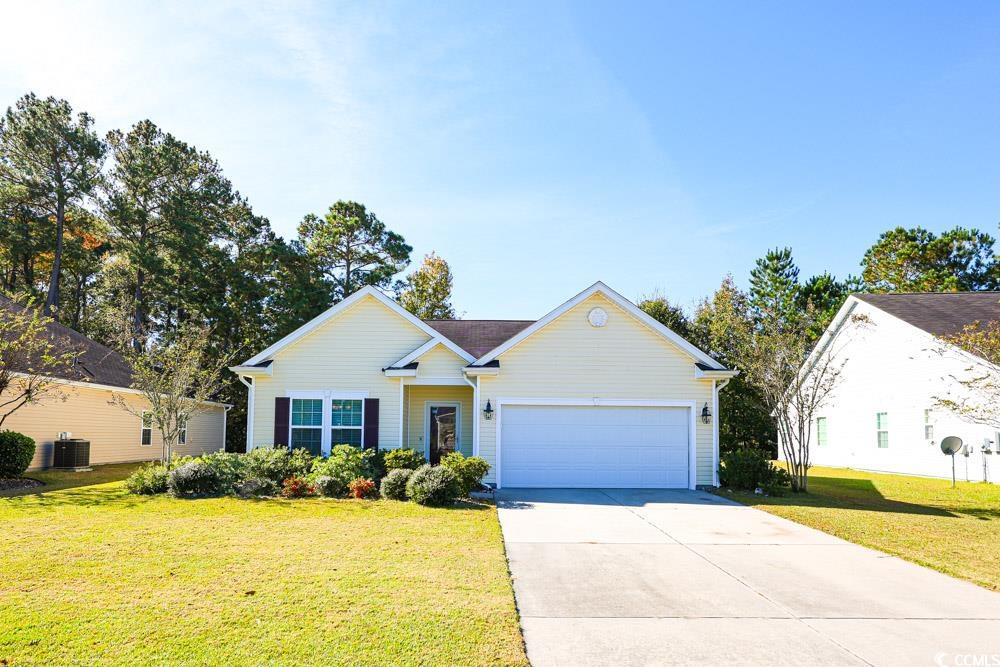 View of front of house featuring driveway, a front yard, and an attached garage