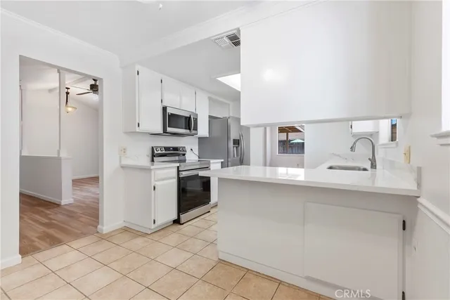 a kitchen with granite countertop a sink a counter top space stainless steel appliances and cabinets