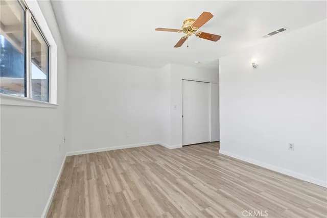 an empty room with wooden floor and ceiling fan