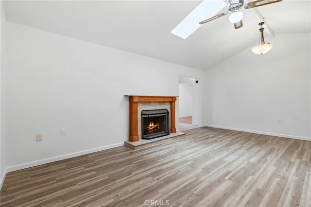 a view of an empty room with wooden floor fireplace and a window