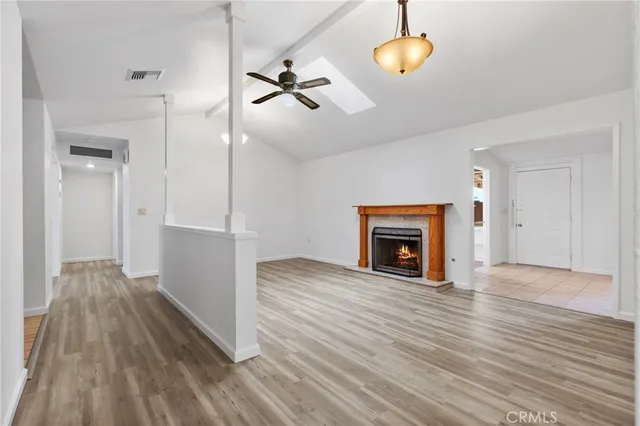 a view of an empty room with wooden floor fireplace and a window
