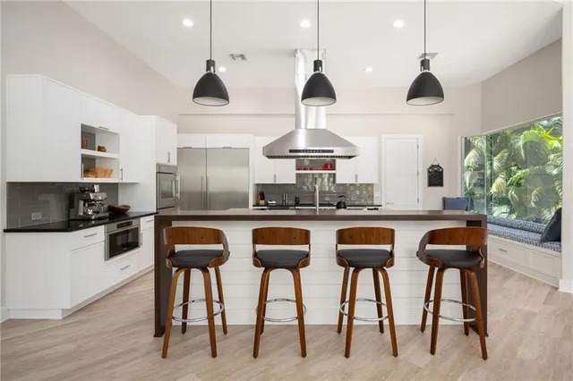 a kitchen with stainless steel appliances kitchen island granite countertop a table chairs sink and cabinets