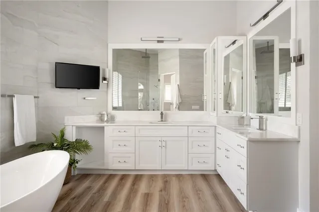 a spacious bathroom with a double vanity sink a mirror a bathtub and a shower