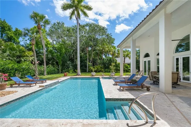 a view of swimming pool with lawn chairs and a patio
