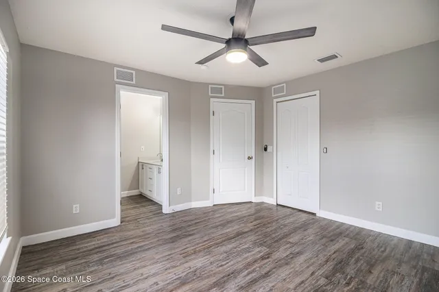 an empty room with wooden floor and ceiling fan