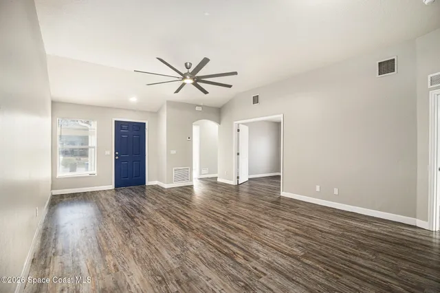 a view of an empty room with window and wooden floor