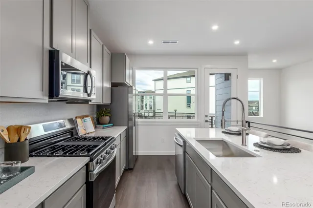 a kitchen with stainless steel appliances kitchen island granite countertop a sink and a stove top oven with wooden floor