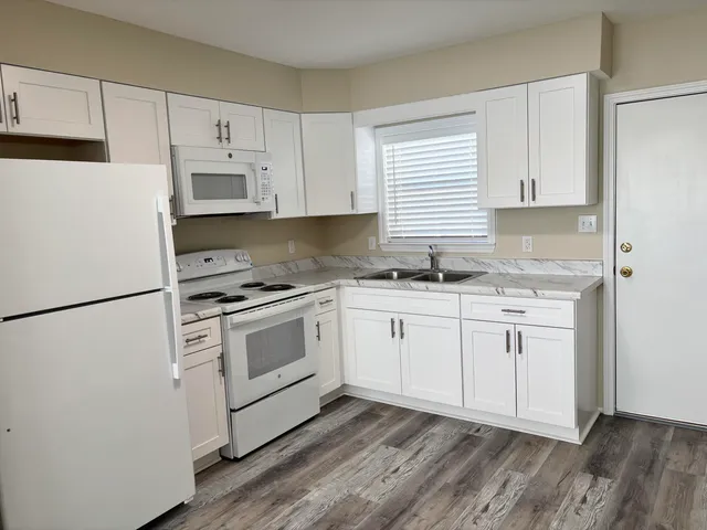 a kitchen with granite countertop white cabinets and white appliances