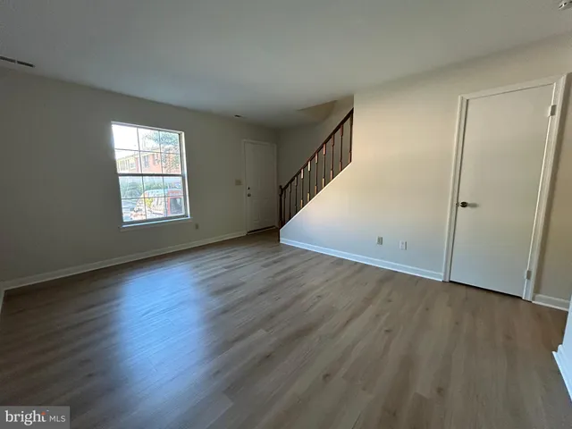 an empty room with wooden floor and window