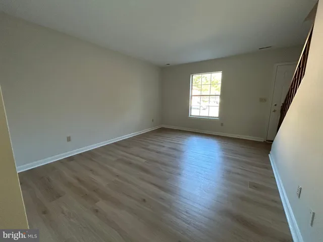 a view of an empty room with wooden floor and window
