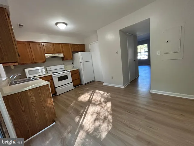 a kitchen with wooden floors and white walls
