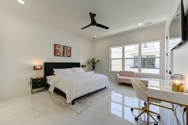 a bedroom with a bed a flat screen tv and a chandelier