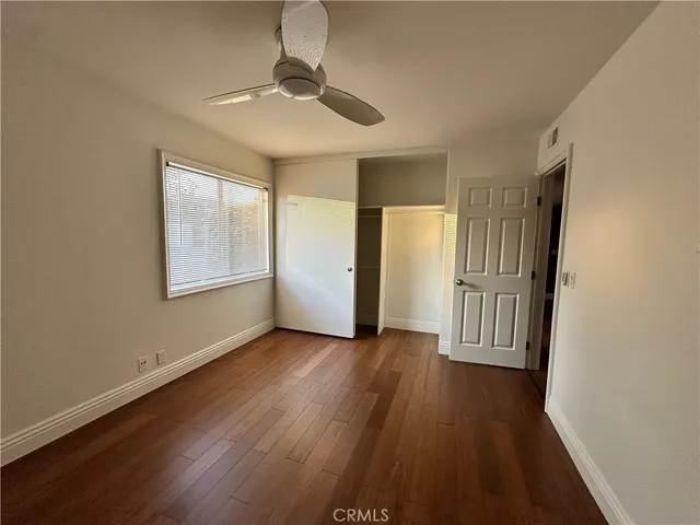 an empty room with wooden floor chandelier and windows