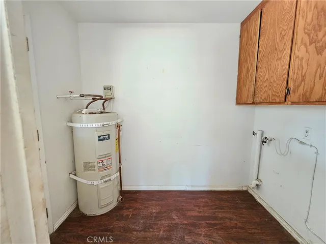 a room with water heater and wooden cabinets