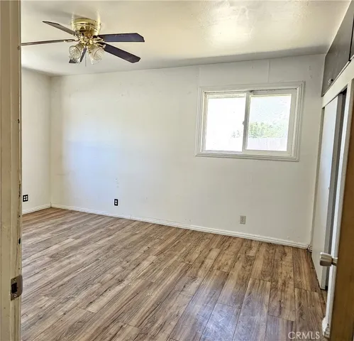 a view of a room with wooden floor and a ceiling fan