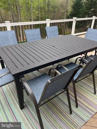 a balcony with wooden floor outdoor seating and yard in the back